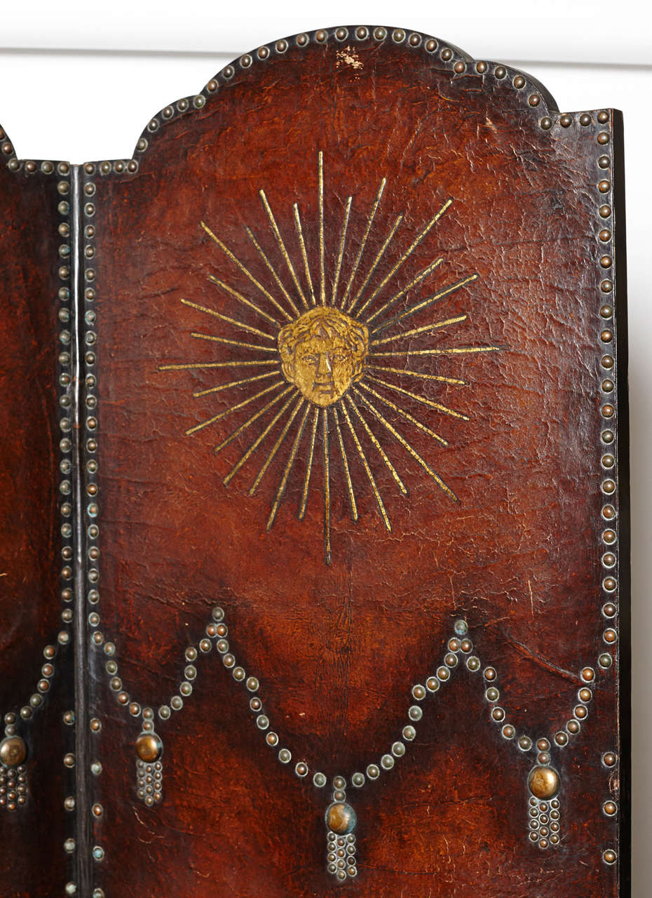 Leather screen has four panels with brass studs and gold painted designs.